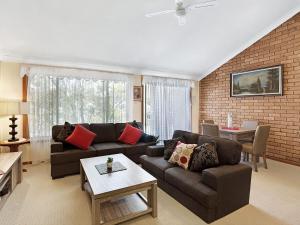 a living room with couches and a brick wall at Macadamia Court 2 8 Government Road in Nelson Bay