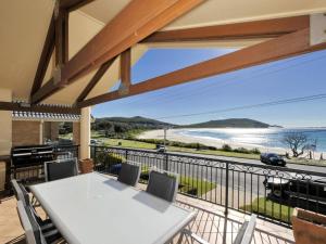 a balcony with a table and chairs and a view of the ocean at Marine Dr 2 70 Fingal Bay in Fingal Bay