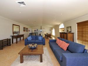 ein Wohnzimmer mit blauen Sofas und einem Tisch in der Unterkunft Marine Dr 2 70 Fingal Bay in Fingal Bay
