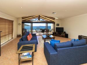 a living room with blue couches and a view of the ocean at Marine Dr 2 70 Fingal Bay in Fingal Bay