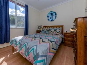 a bedroom with a bed and a dresser and a window at Marine Drive 32 in Fingal Bay