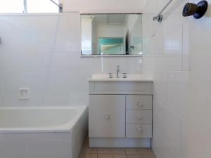 a white bathroom with a sink and a tub and a mirror at Marine Drive 32 in Fingal Bay +9 photos