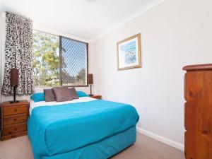 a bedroom with a blue bed and a window at Mistral Court Unit 16 17 Mistral Close in Nelson Bay