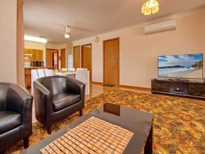 a living room with two chairs and a flat screen tv at Nelson Street 19 in Nelson Bay