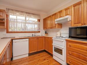 a kitchen with wooden cabinets and a white stove top oven at Nelson Street 19 in Nelson Bay
