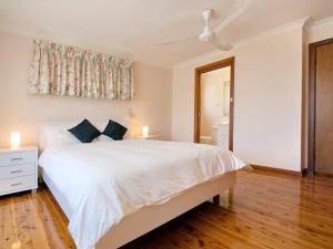 a white bedroom with a large white bed and wooden floors at Nelson Street 19 in Nelson Bay