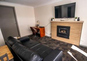 a living room with a leather couch and a fireplace at Snow Gum Apartment 2 in Baw Baw Village