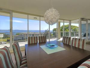 a dining room table with chairs and a chandelier at Oasis Unit 9 5 Laman Street in Nelson Bay