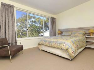a bedroom with a bed and a large window at Ocean View Oasis at Fingal Bay in Fingal Bay
