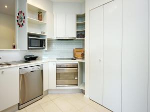 une cuisine avec des armoires blanches et un four à plaques de cuisson dans l'établissement Pacific Blue Apartment 258, 265 Sandy Point Road, à Salamander Bay