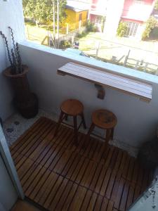 una mesa y dos taburetes sentados bajo una ventana en Linda kitnet perto do mar! en Tramandaí