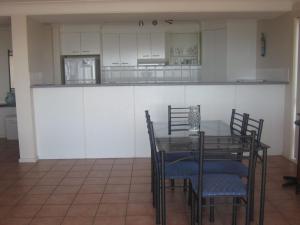 a dining room with a table and chairs and a kitchen at Palm Beach 33B Shoal Bay Road in Shoal Bay