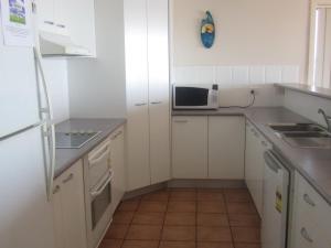 a small kitchen with white cabinets and a microwave at Palm Beach 33B Shoal Bay Road in Shoal Bay