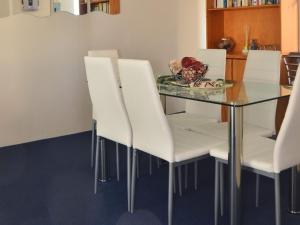 comedor con mesa de cristal y sillas blancas en Parkview Unit 16 11 Catalina Close, en Nelson Bay
