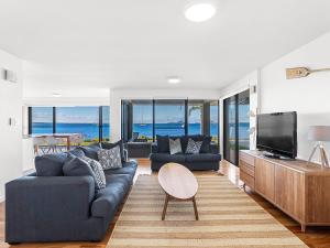a living room with a blue couch and a tv at Panarea Soldiers Point Road Unit 1 197 in Salamander Bay