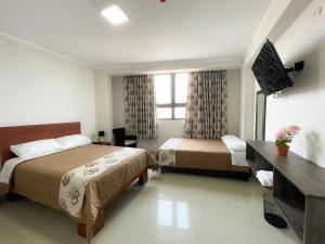 a hotel room with two beds and a television at Gran Caral Hotel in Barranca