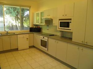 a kitchen with white cabinets and a sink and a microwave at Pelicans Perch 8 Verona Road in Shoal Bay