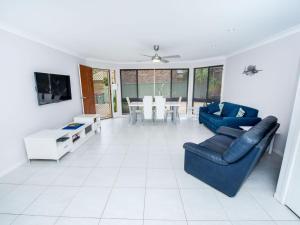 a living room with two blue couches and a table at Pet Friendly Tomaree Rd 142 Shoal Bay in Shoal Bay