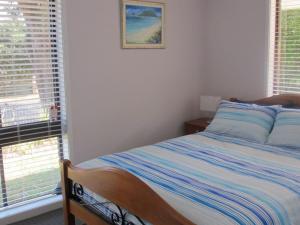 sypialnia z łóżkiem i 2 oknami w obiekcie Pet Friendly Tomaree Rd 142 Shoal Bay w mieście Shoal Bay