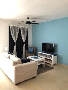 a living room with a white couch and a tv at Bayahibe Apartment in Cadaques in Bayahibe