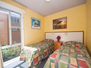 1 dormitorio con 2 camas individuales y ventana en Castaways Unit 4 17 Shoal Bay Road, en Shoal Bay