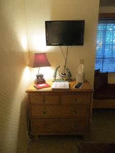 a lamp on top of a dresser with a tv on the wall at Donner Lake Inn B&B in Truckee