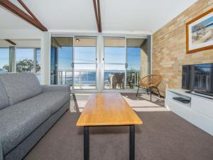 a living room with a couch and a table at Castaways Unit 8 17 Shoal Bay Road in Shoal Bay