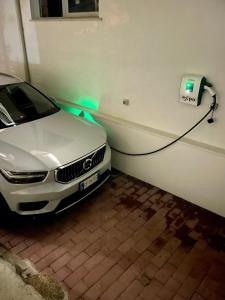 ザンブローネにあるPark Oasi Resortの白い車が電気自動車の充電器に差し込まれています