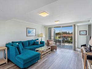 sala de estar con sofá azul y mesa en Cirrus 6 44 Marine Drive, en Fingal Bay