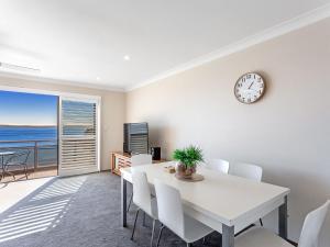 a dining room with a table and a clock on the wall at Collendina Unit 6 19 Kurrawa Close in Nelson Bay