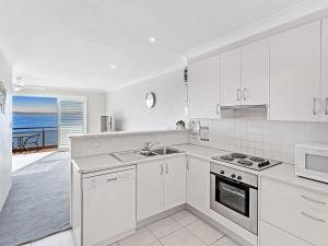 a kitchen with white cabinets and a view of the ocean at Collendina Unit 6 19 Kurrawa Close in Nelson Bay