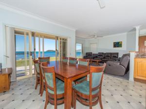 a dining room with a table and chairs and the ocean at Cook Street 4 in Salamander Bay