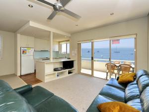 a living room with a blue couch and a kitchen at Del Rae Unit 12 25 Shoal Bay Road in Shoal Bay