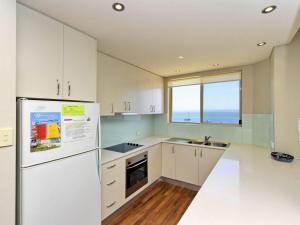 a white kitchen with a refrigerator and a window at Del Rae Unit 12 25 Shoal Bay Road in Shoal Bay +1 photo