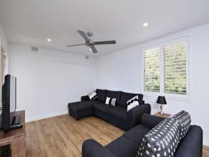 a living room with a black couch and a ceiling fan at Del Rae Unit 18 25 Shoal Bay Road in Shoal Bay