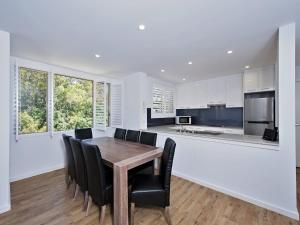 a kitchen with a wooden table and black chairs at Del Rae Unit 18 25 Shoal Bay Road in Shoal Bay