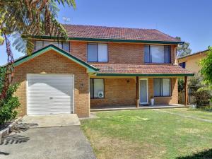 una casa in mattoni rossi con un garage bianco di Eden by the Bay 98 Sandy Point Road a Corlette