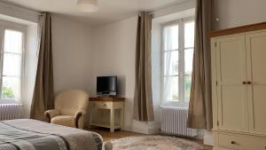 um quarto com uma cama, uma televisão e uma cadeira em Ferme de La Croix em Brion-près-Thouet