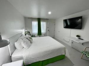 a bedroom with a white bed with a tv on the wall at Loma Linda Inn in San Bernardino