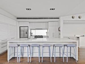 a kitchen with a large white island with purple bar stools at The Belmond in Portsea