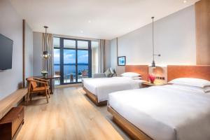 淳安県にあるvoco Thousand Island Lake, an IHG Hotelのベッド2台、デスク、テレビが備わるホテルルームです。