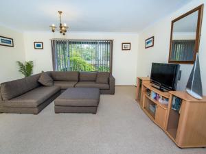 a living room with a couch and a television at Government Rd 63 Shoal Bay in Shoal Bay