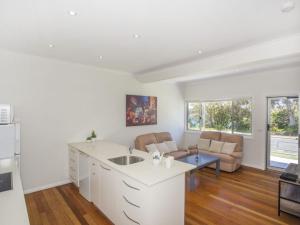 a kitchen with a sink and a living room at Harbour Breeze in Ulladulla