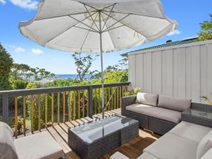 a patio with a couch and an umbrella at Fairwater In Mollymook in Mollymook