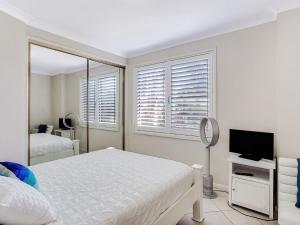 a white bedroom with a bed and a television at Sandy Shores 1 3 Messines Street in Shoal Bay