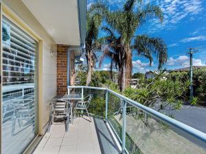 a balcony with a table and chairs and a palm tree at Sandy Shores 1 3 Messines Street in Shoal Bay