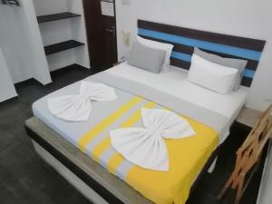 a bed with two white towels on top of it at Le Petit Hotel & Restaurant in Negombo