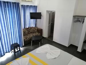 a room with a bed and a couch and a tv at Le Petit Hotel & Restaurant in Negombo