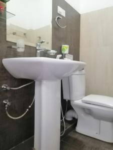 a bathroom with a white sink and a toilet at Le Petit Hotel & Restaurant in Negombo