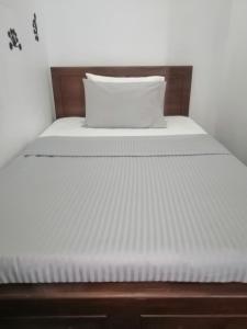 a bed with white sheets and a pillow at Le Petit Hotel & Restaurant in Negombo